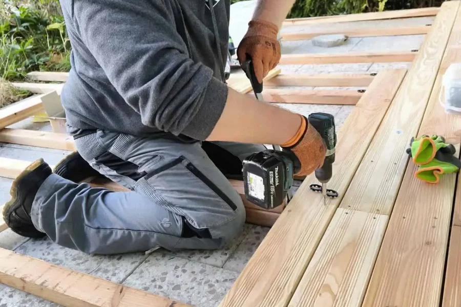 Handwerker verschraubt Holzdielen beim professionellen Terrassenbau in Rohrdorf nahe Rosenheim.