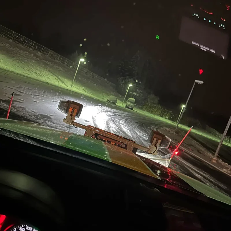 Blick aus einem Räumfahrzeug mit Schneepflug bei Nacht während des Winterdienstes in Rohrdorf bei Rosenheim.